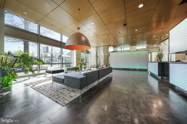 a living room with couches and kitchen view with large windows