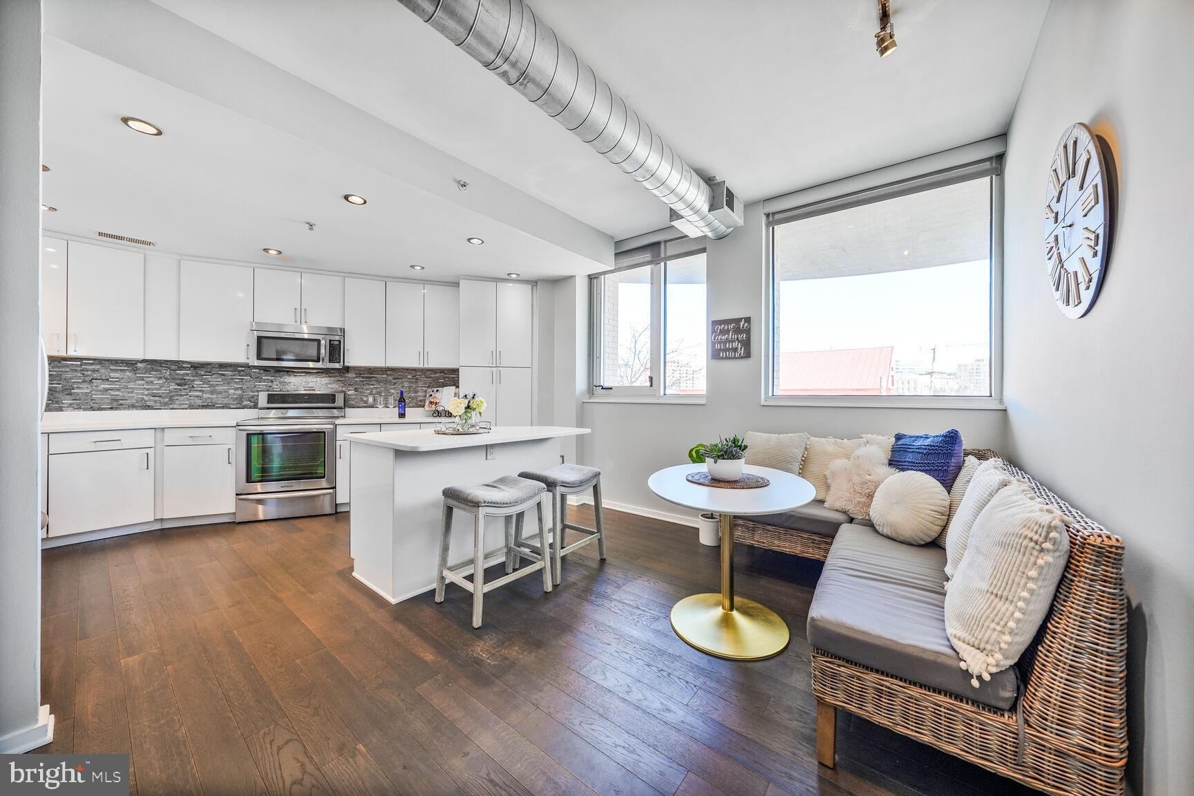 3409 Wilson Boulevard, Unit 211 Arlington, VA 22201 - Photo 5 of 30 a kitchen with stainless steel appliances granite countertop wooden floors a microwave a stove and white cabinets