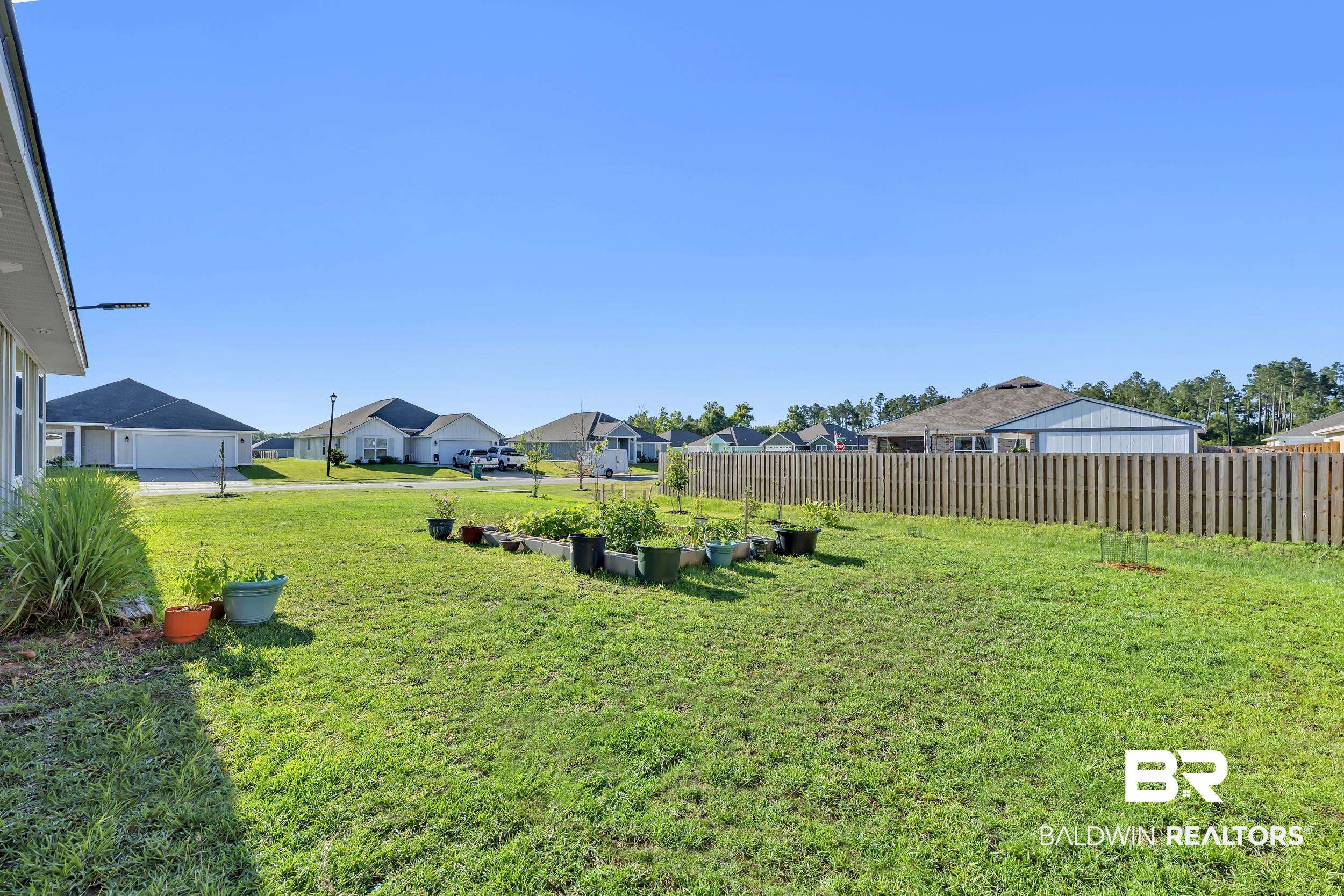 1228 Caper Avenue Foley, AL 36535 - Photo 36 of 54 Expansive green lawn with a wooden privacy fence bordering the rear property line