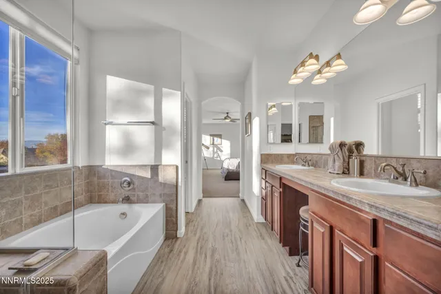 a bathroom with a tub double vanity sink and a large mirror