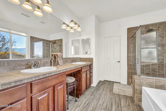 a spacious bathroom with a granite countertop double vanity sink a mirror and a shower