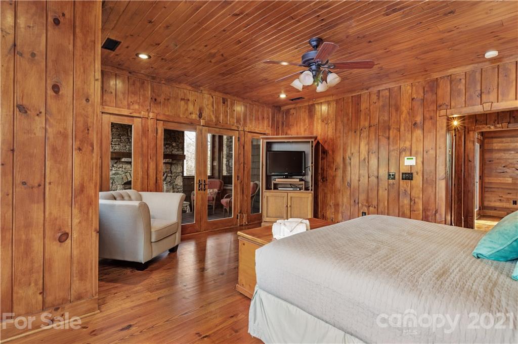 471 Chestnut Hill Loop Road Gerton, NC 28735 - Photo 32 of 45 a spacious bedroom with a large bed a chandelier and flat screen tv