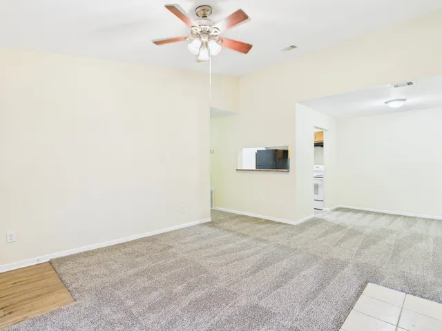 a view of a big room with wooden floor and a chandelier fan
