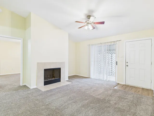 a view of an empty room with chandelier fan and fire place