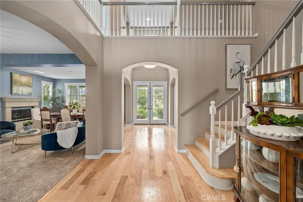 a kitchen with stainless steel appliances kitchen island granite countertop a refrigerator a stove a sink and white cabinets with wooden floor