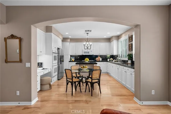 a kitchen with a refrigerator a sink dishwasher a oven and a dining table with wooden floor