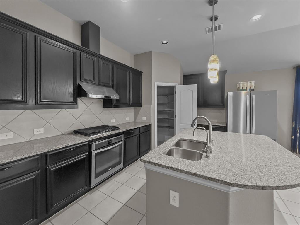 3205 Ridgeway Drive McKinney, TX 75071 - Photo 10 of 27 a kitchen with stainless steel appliances granite countertop a sink a stove and a refrigerator