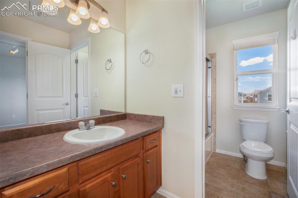 6139 Rocking Chair Lane Colorado Springs, CO 80925 - Photo 14 of 17 a bathroom with a granite countertop sink a toilet and a mirror
