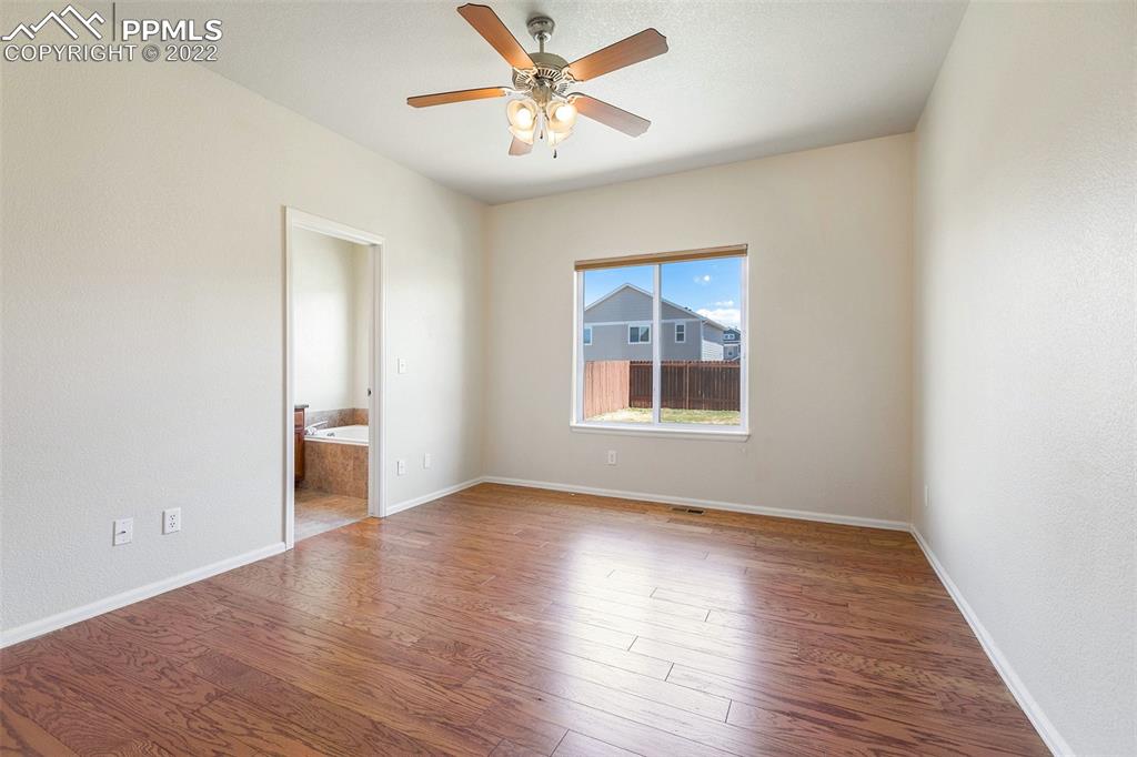 6139 Rocking Chair Lane Colorado Springs, CO 80925 - Photo 4 of 17 an empty room with wooden floor chandelier fan and windows