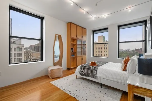 a bedroom with a bed and a large mirror next to a window