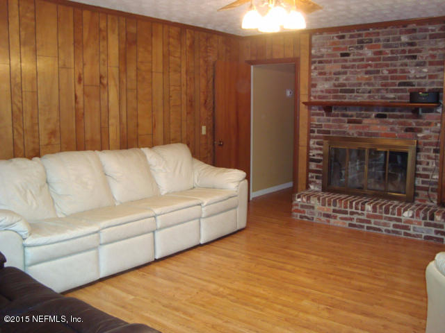 6910 Hermitage Road Jacksonville, FL 32277 - Photo 8 of 42 a living room with furniture a fireplace and a chandelier
