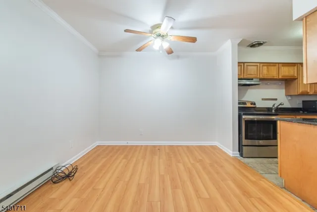 a view of kitchen and empty room with wooden floor