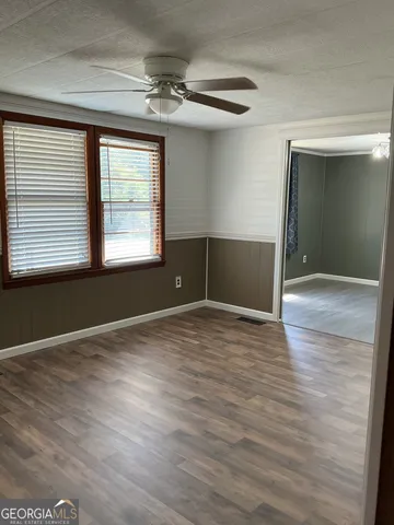a view of empty room with wooden floor and fan