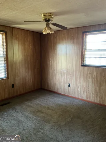 an empty room with a chandelier fan and windows