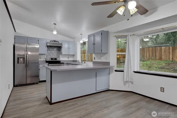 a kitchen with stainless steel appliances granite countertop a refrigerator a stove a sink and a large window