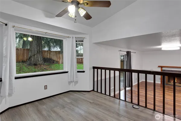 a view of a room with wooden floor fan and windows