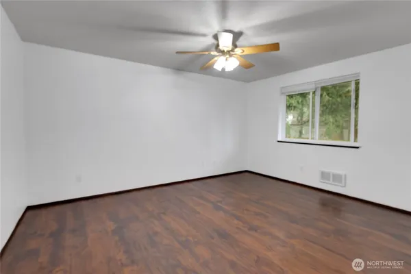 an empty room with wooden floor chandelier fan and windows