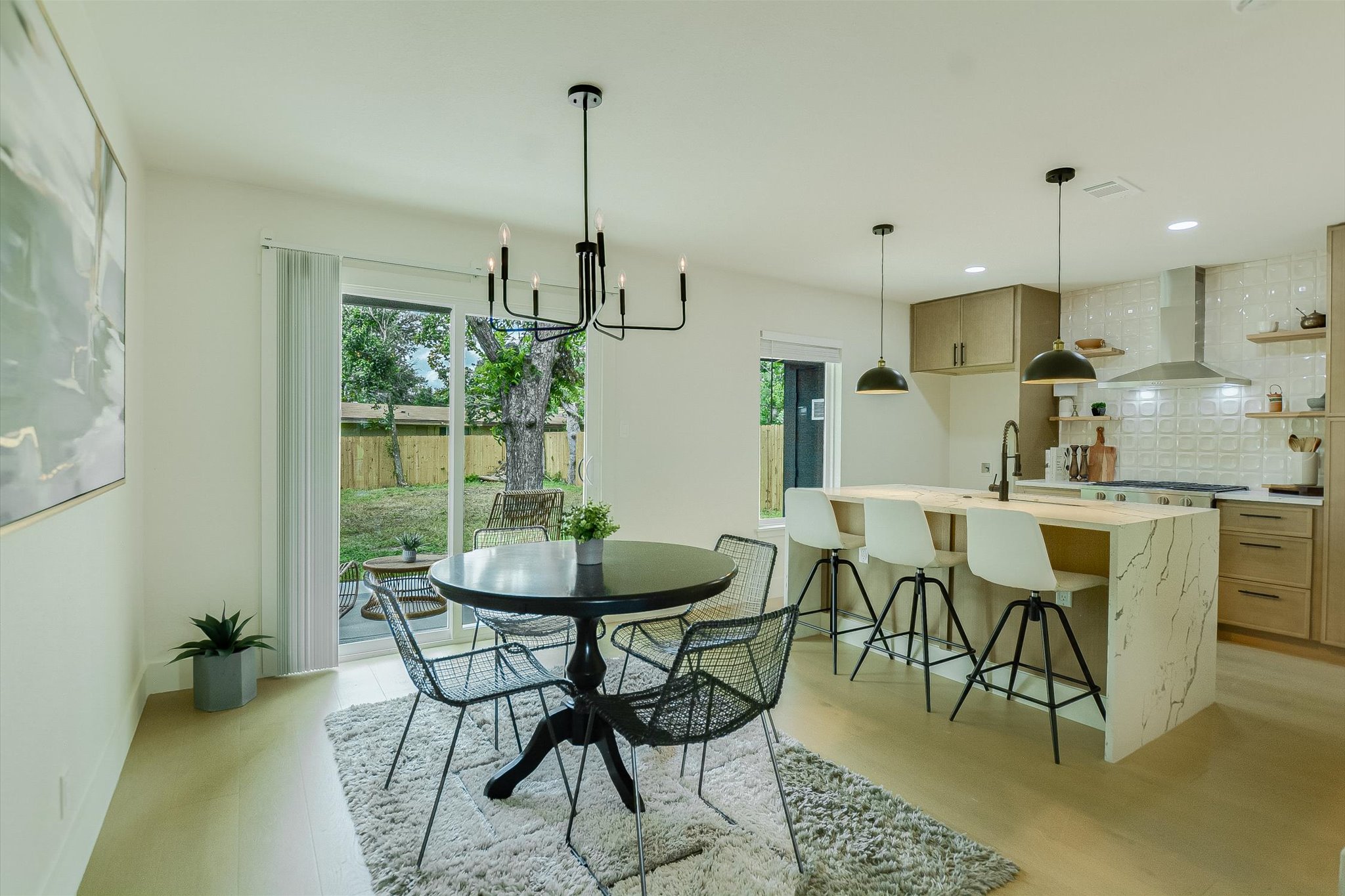 4505 Kitty Avenue Austin, TX 78721 - Photo 2 of 11 An open-concept living area with a sleek dining set and a modern kitchen island, all bathed in natural light.