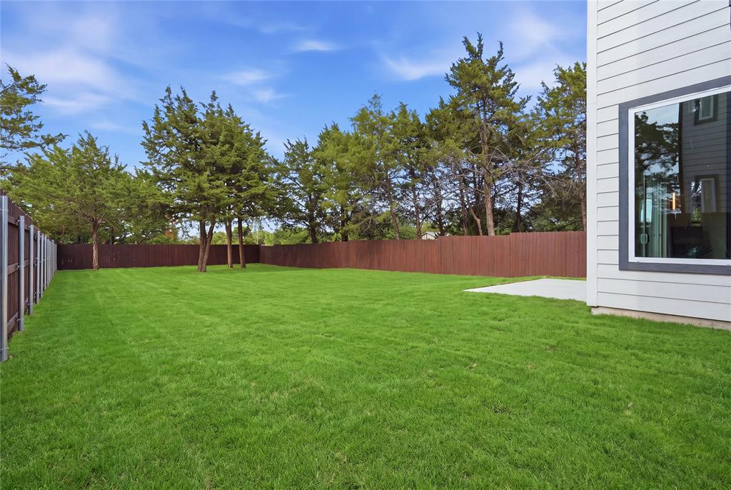 3905 Blue Ridge Boulevard Dallas, TX 75233 - Photo 23 of 25 Expansive green lawn with a privacy fence, mature trees, and a concrete patio