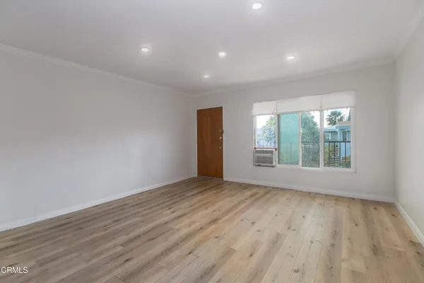 a view of an empty room with wooden floor and a window
