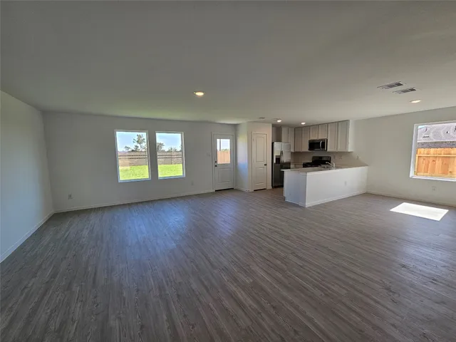 a view of a kitchen and an empty room with a window