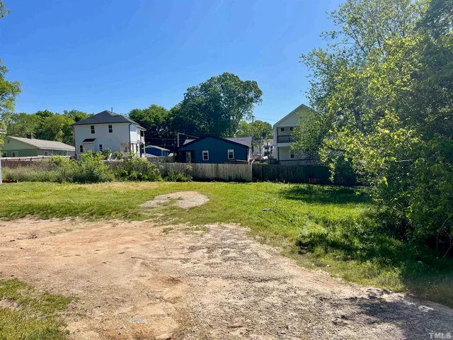 a view of a yard with plants and a brick wall