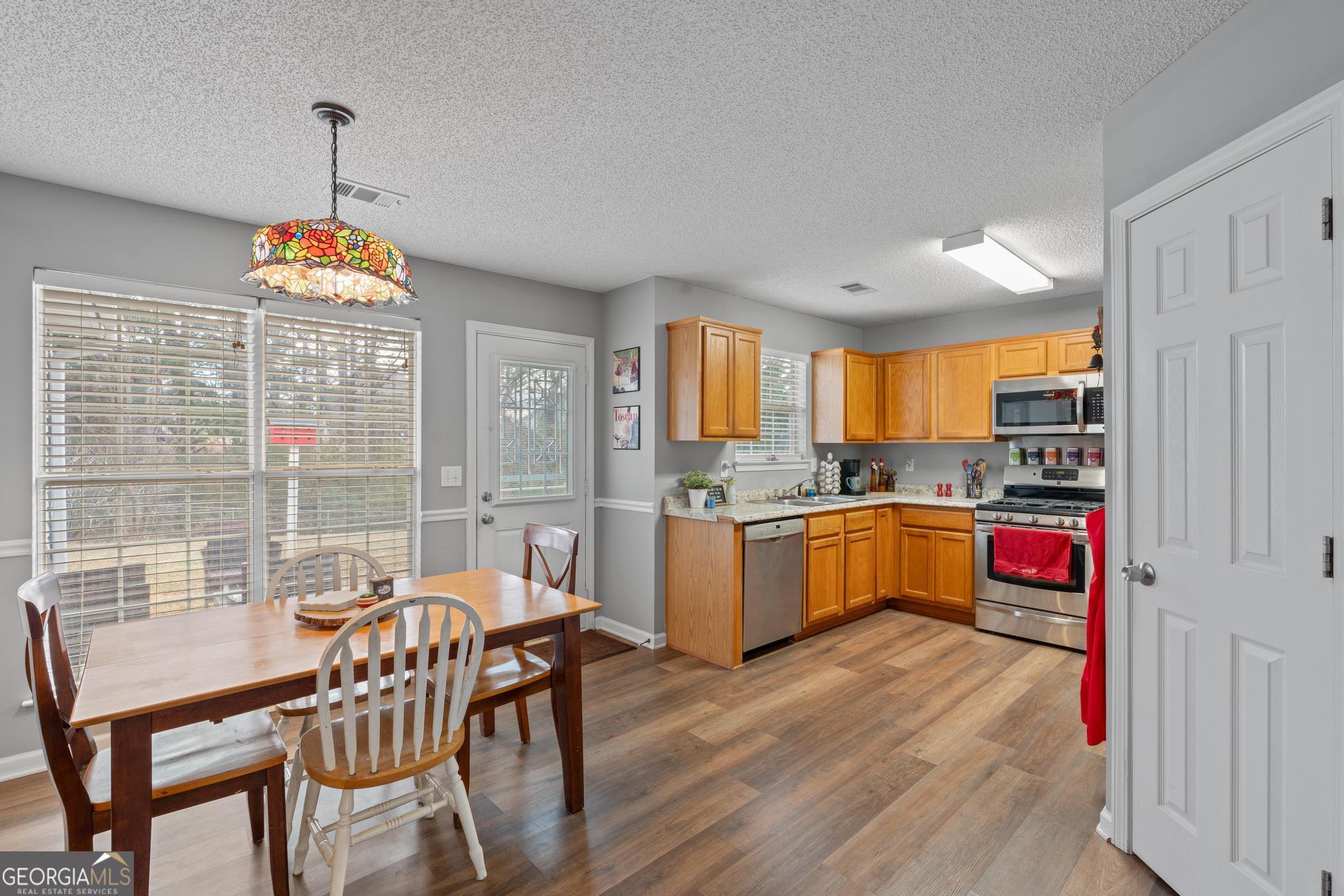 340 Harris Avenue Locust Grove, GA 30248 - Photo 11 of 41 a kitchen with stainless steel appliances granite countertop a stove a refrigerator a kitchen island a dining table and chairs