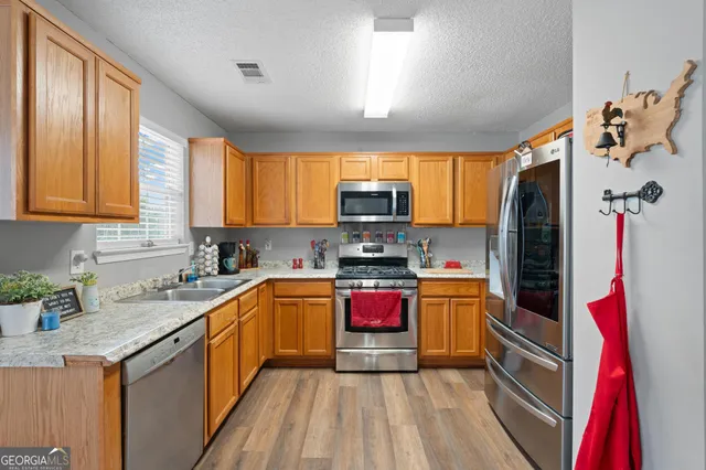 a kitchen with stainless steel appliances granite countertop dining table chairs sink and wooden floor