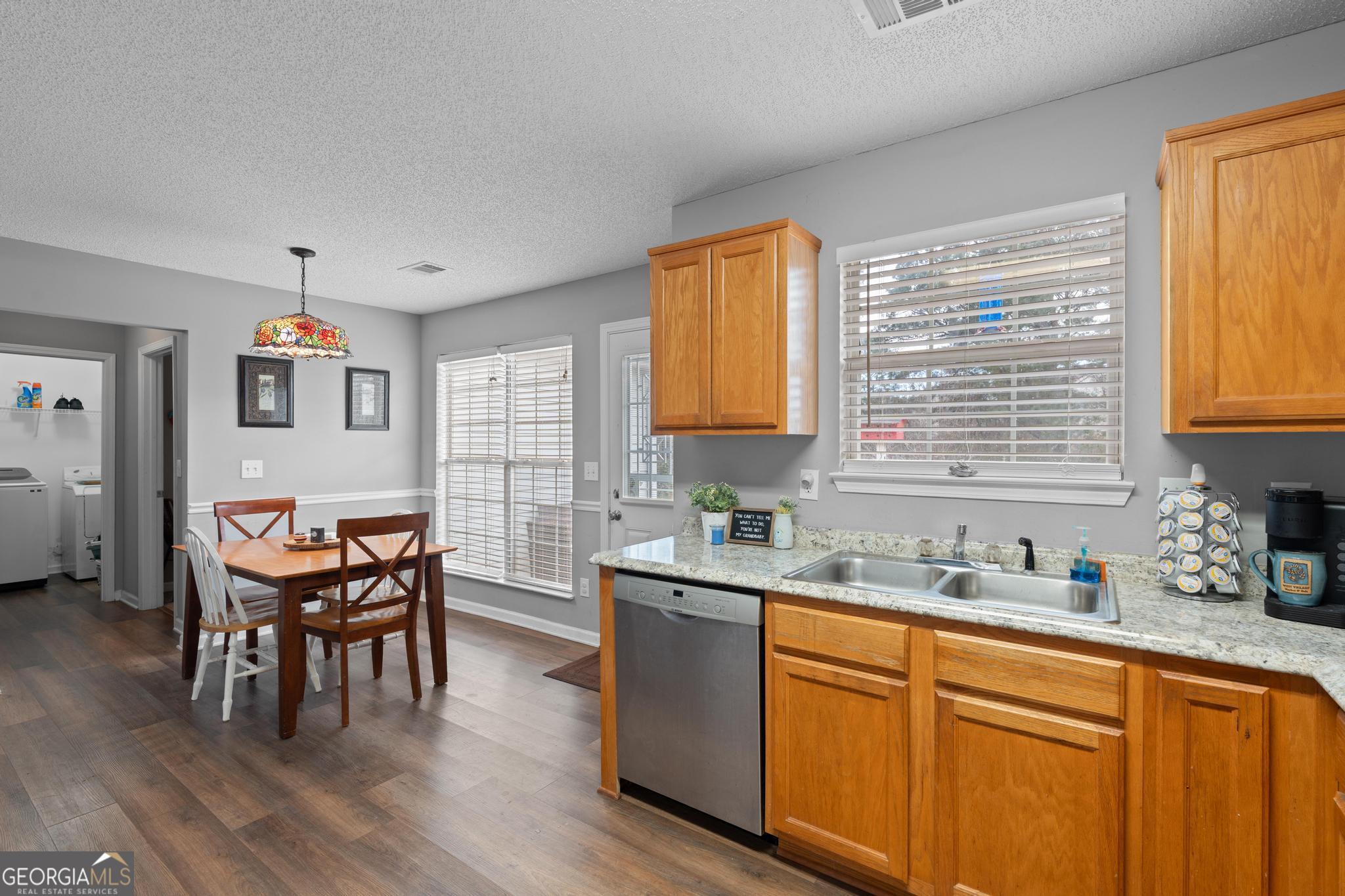 340 Harris Avenue Locust Grove, GA 30248 - Photo 16 of 41 a kitchen with stainless steel appliances granite countertop dining table chairs sink and wooden floor