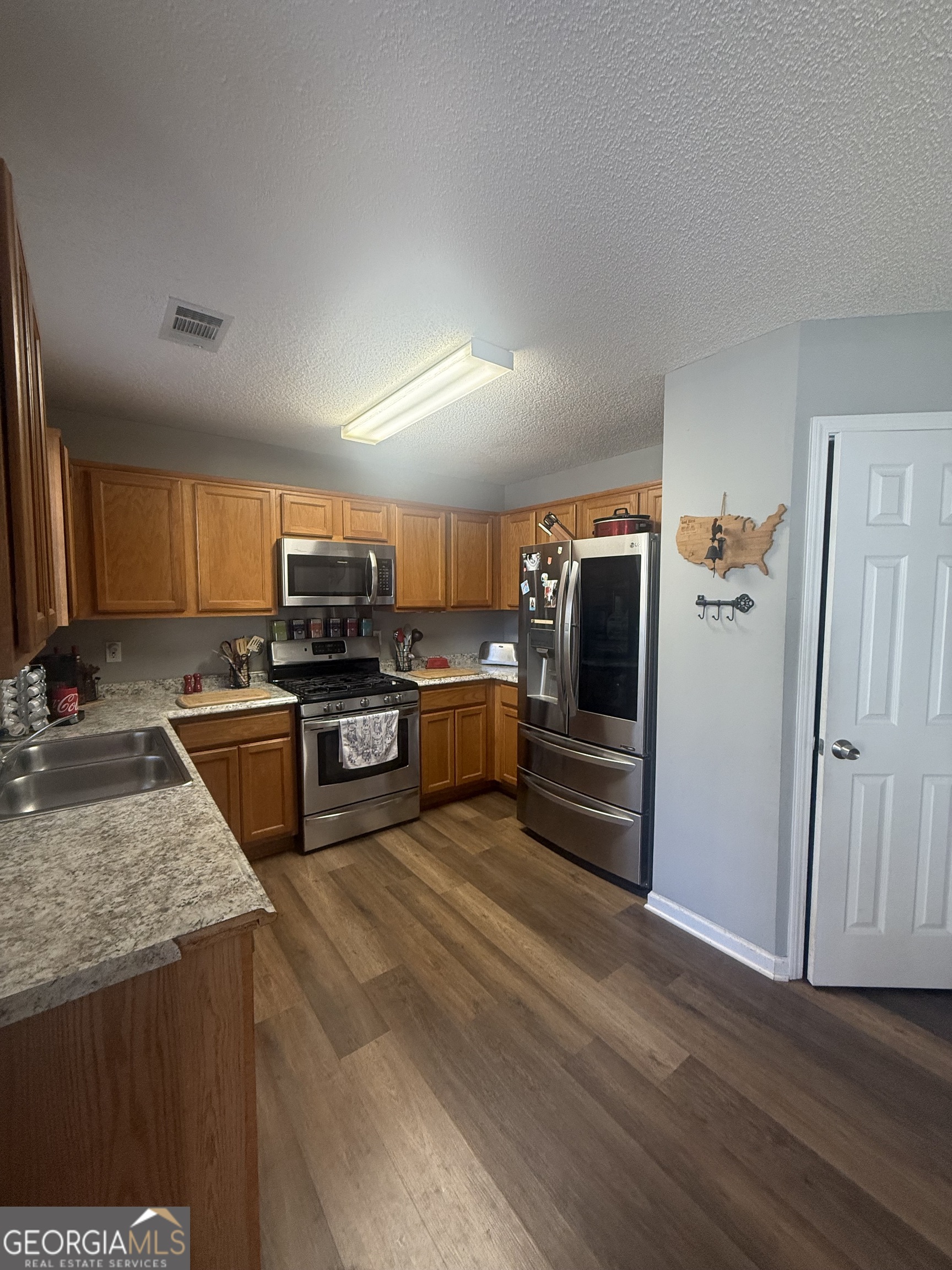 340 Harris Avenue Locust Grove, GA 30248 - Photo 4 of 24 a kitchen with granite countertop a refrigerator and a sink