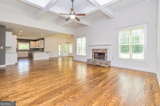 an empty room with wooden floor fireplace and windows