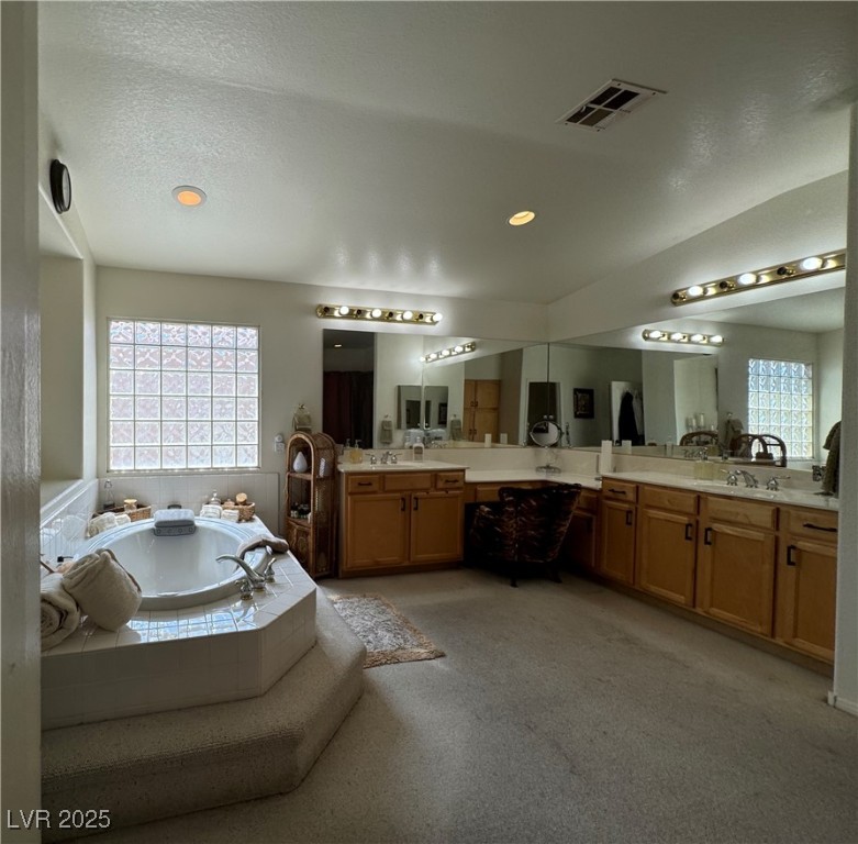 420 Rhythm Street Henderson, NV 89074 - Photo 11 of 27 Full bath with a bath, two vanities, a textured ceiling, and recessed lighting