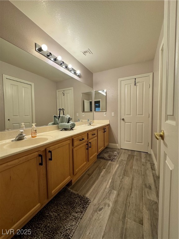 420 Rhythm Street Henderson, NV 89074 - Photo 18 of 27 Full bath with dark wood-type flooring, double vanity, and a textured ceiling
