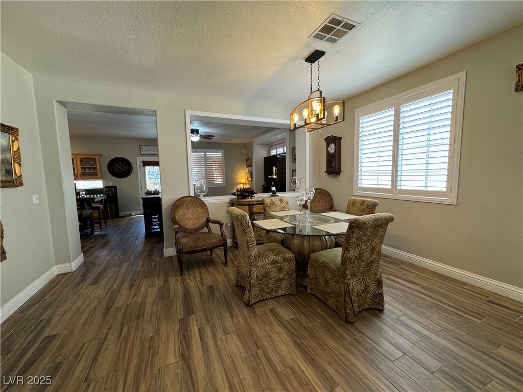 420 Rhythm Street Henderson, NV 89074 - Photo 3 of 27 Dining area featuring a textured ceiling, dark wood-style flooring, plenty of natural light, a chandelier, and ceiling fan
