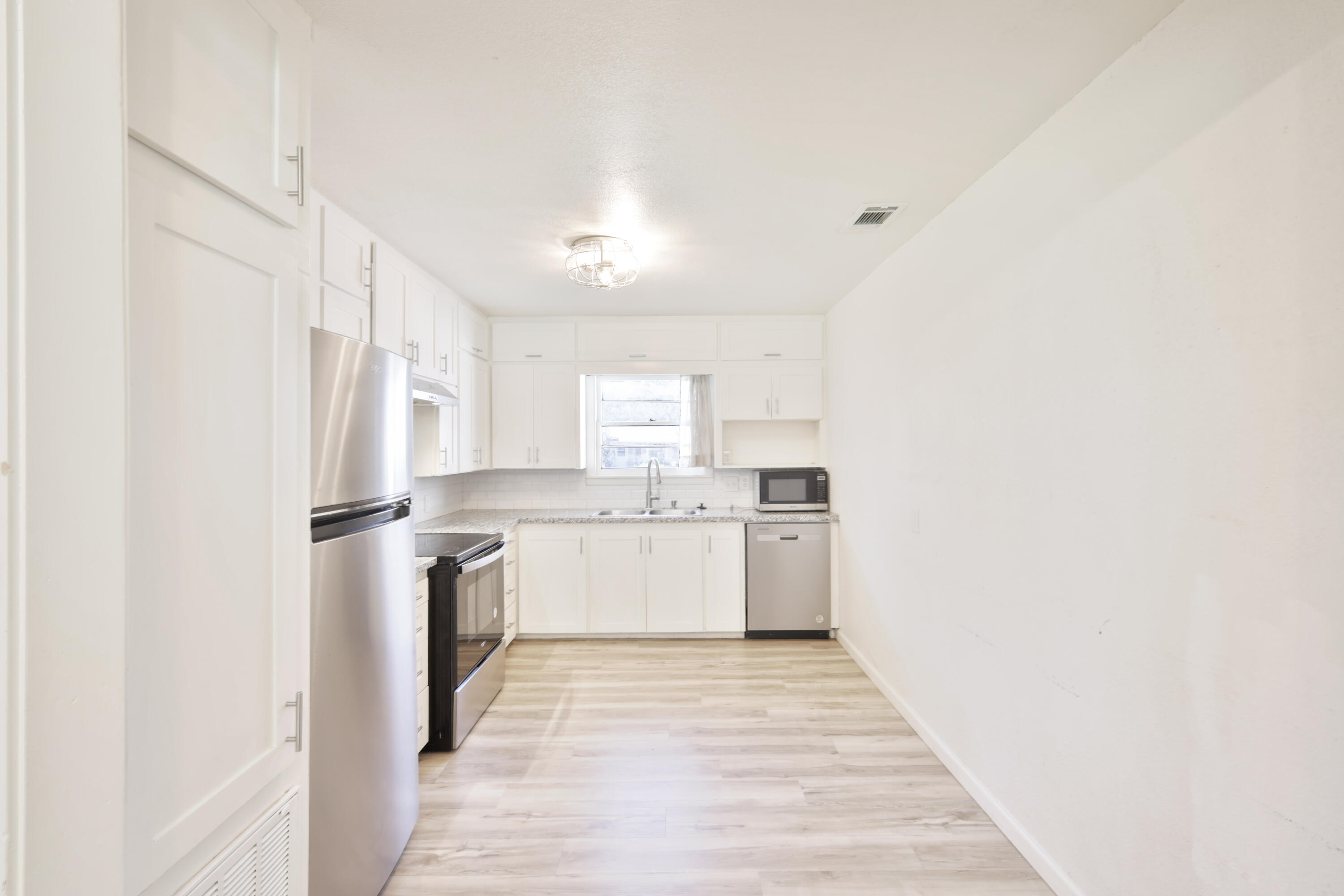3812 31st Street Lubbock, TX 79410 - Photo 3 of 16 a kitchen with a refrigerator a sink and dishwasher with wooden floor