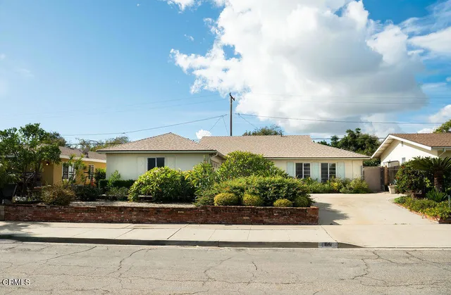 a front view of a house with a yard and potted plants