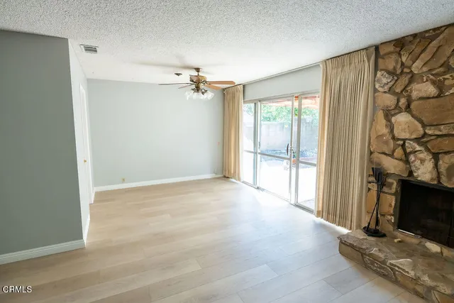 a view of an empty room with a fireplace and a window