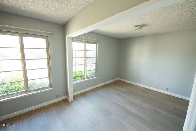 an empty room with wooden floor and windows