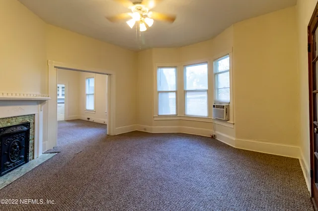 a view of an empty room with a fireplace and a window
