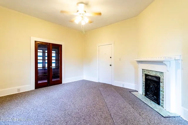 an empty room with a fireplace and chandelier fan