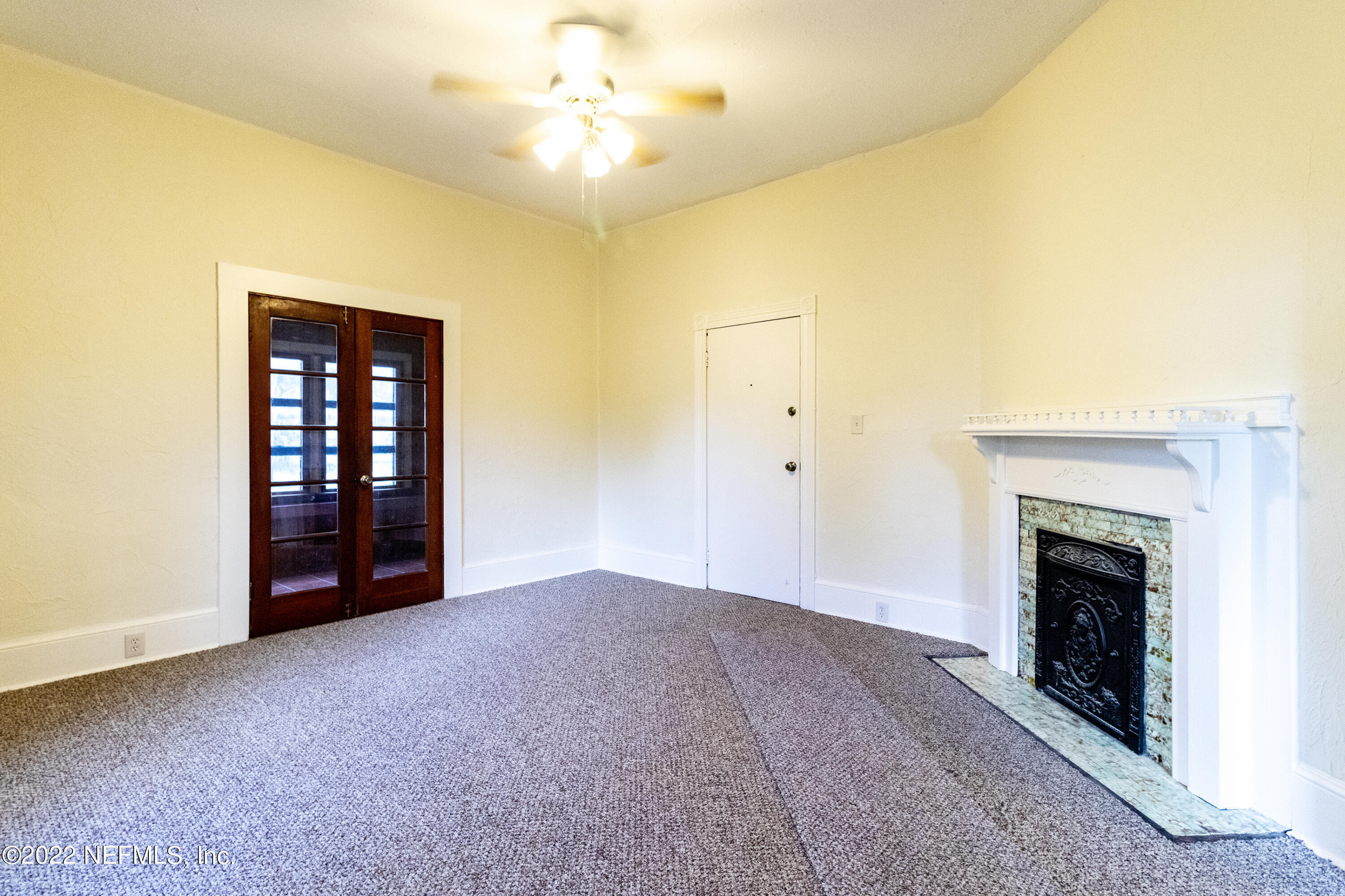 24 Riberia Street, Unit B St. Augustine, FL 32084 - Photo 5 of 19 an empty room with a fireplace and chandelier fan
