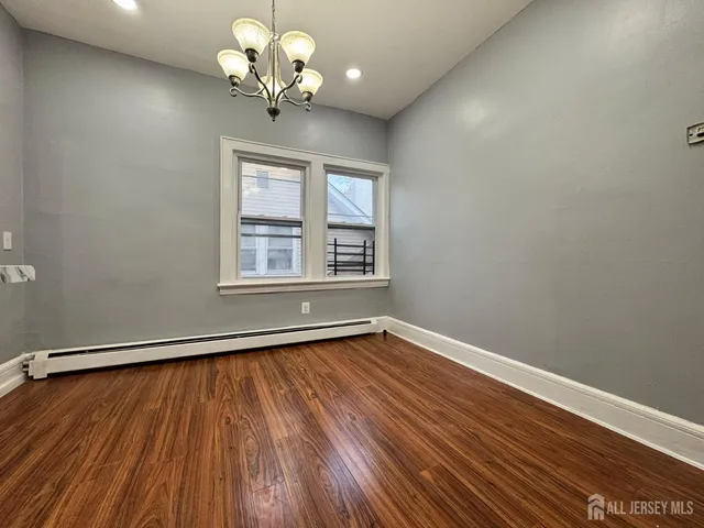a view of a room with wooden floor chandelier and a window
