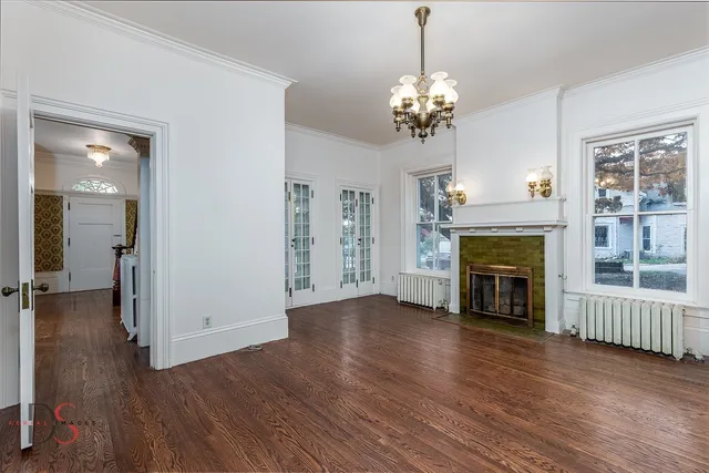 a view of a livingroom with wooden floor a fireplace and windows