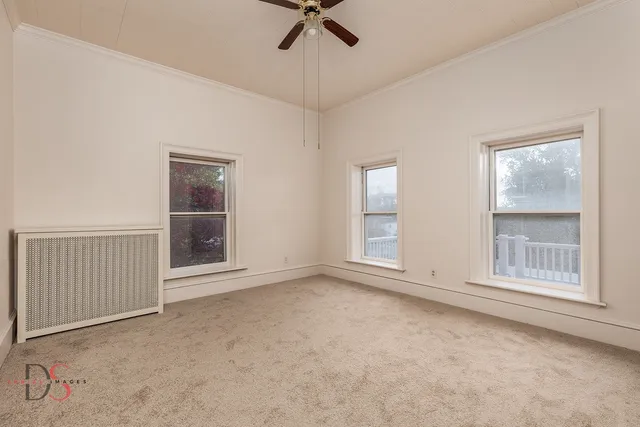 an empty room with windows and fan