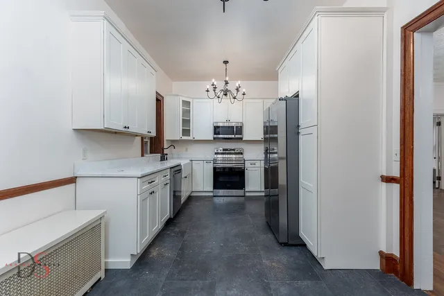 a large kitchen with a lot of white cabinets and stainless steel appliances