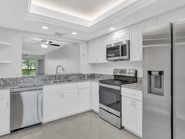 a kitchen with granite countertop white cabinets and stainless steel appliances