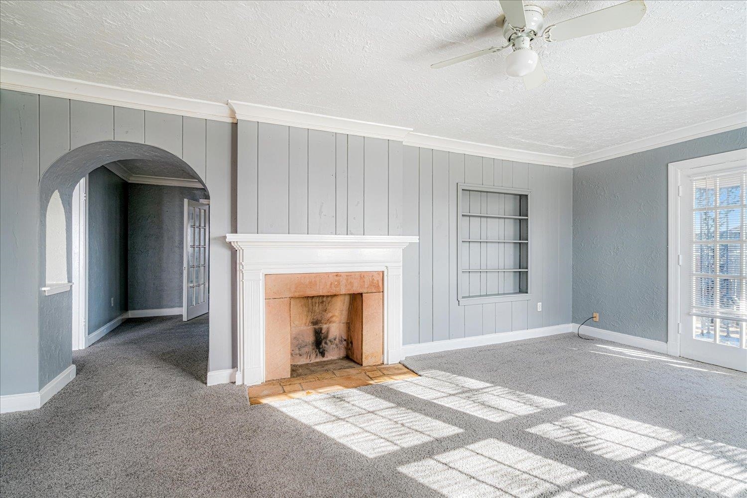 1114 Brownlee Road Memphis, TN 38116 - Photo 10 of 32 Unfurnished living room featuring carpet floors, crown molding, a textured ceiling, arched walkways, and built in features
