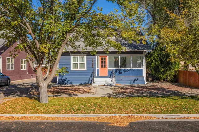 a front view of a house with a yard tree and wooden fence