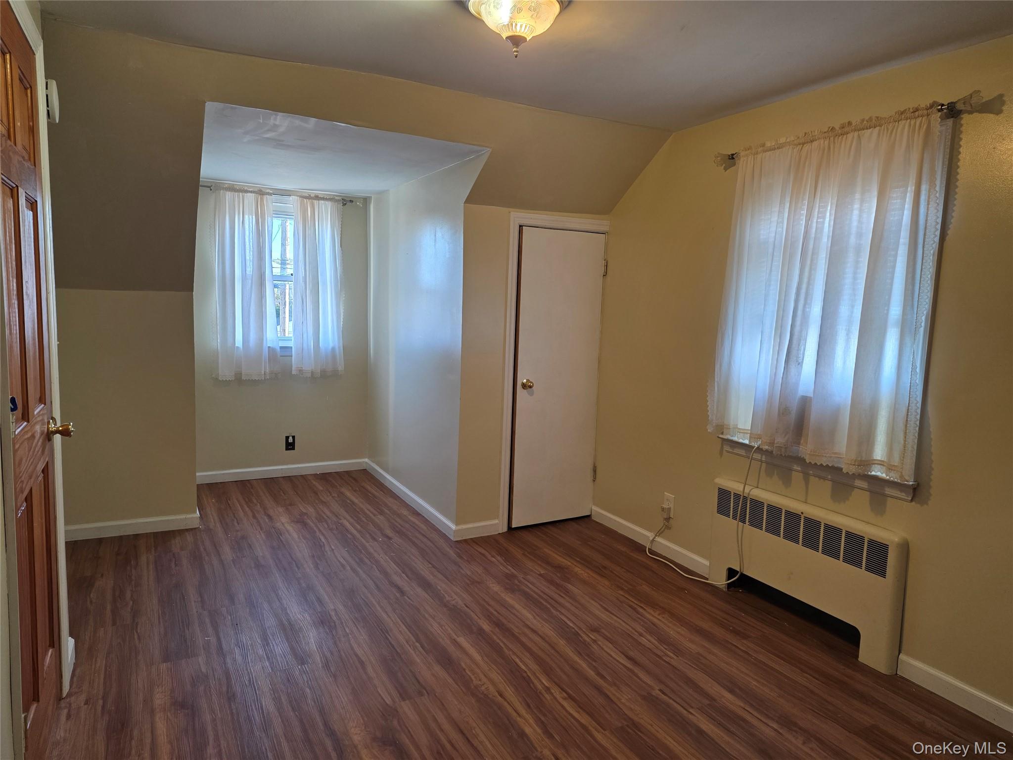 220 Raff Avenue Mineola, NY 11501 - Photo 15 of 22 Bedroom radiator, dark wood-style flooring, and lofted ceiling
