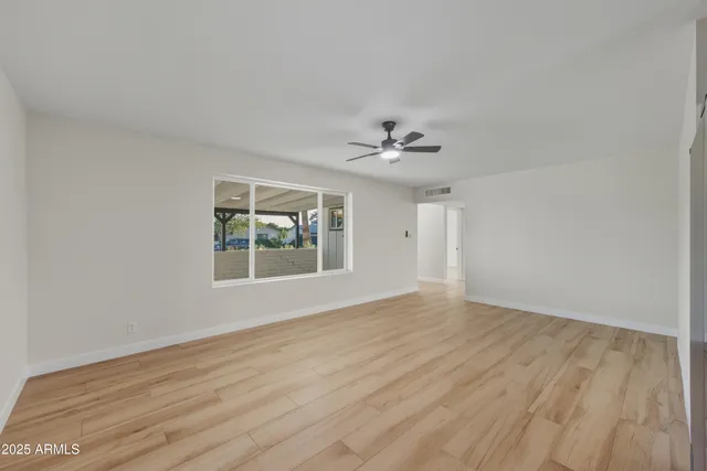 a view of an empty room with wooden floor and a window